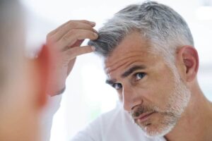 homme qui regarde ses cheveux dans la glace