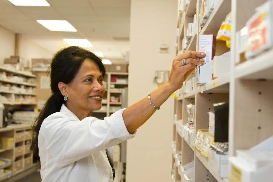 pharmacienne rangeant médicaments dans pharmacie