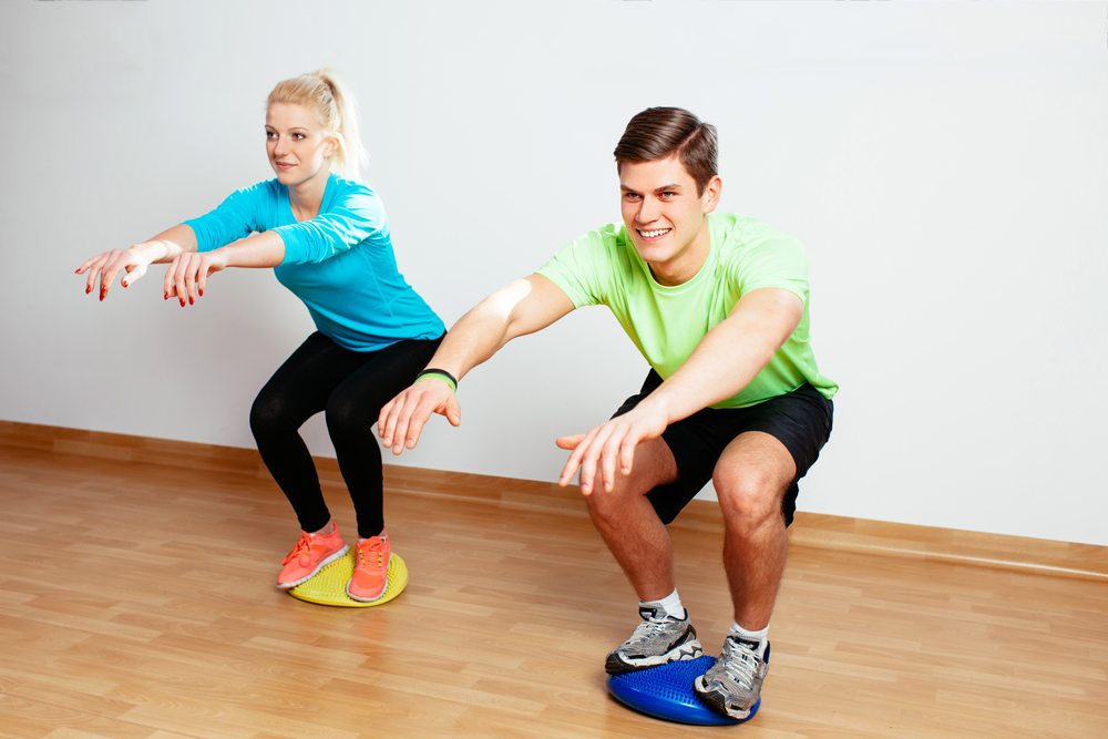 Jeune couple essayant de garder l'équilibre pendant un entraînement de proprioception