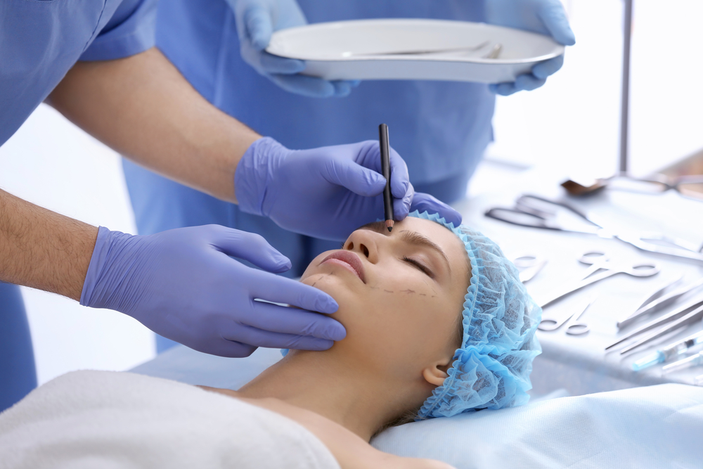 plastic surgeon drawing marks on female face in clinic