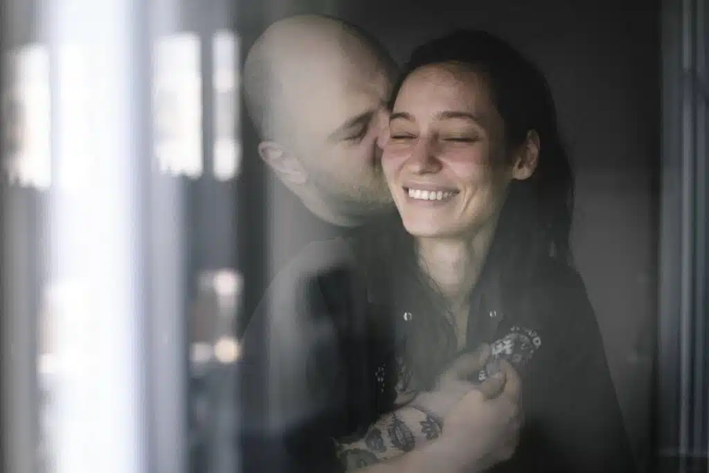 couple amoureux derriere la vitre de la chambre dhotel